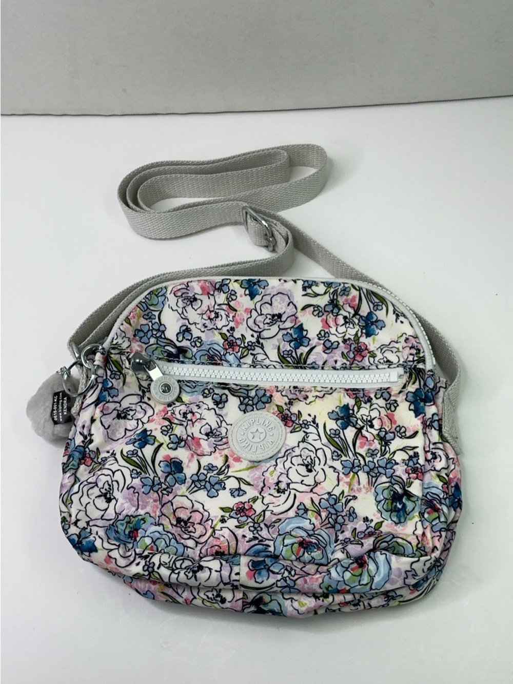 Kipling crossbody bag features a distinctive white-based floral print.
